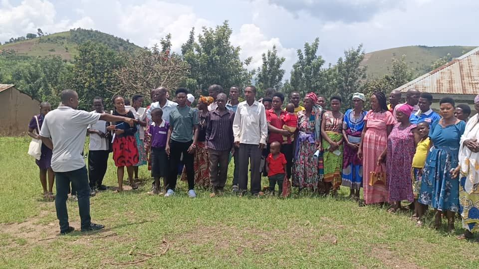 Members of a rural community in Western Uganda gathered outdoors with TVIA staff during an outreach visit